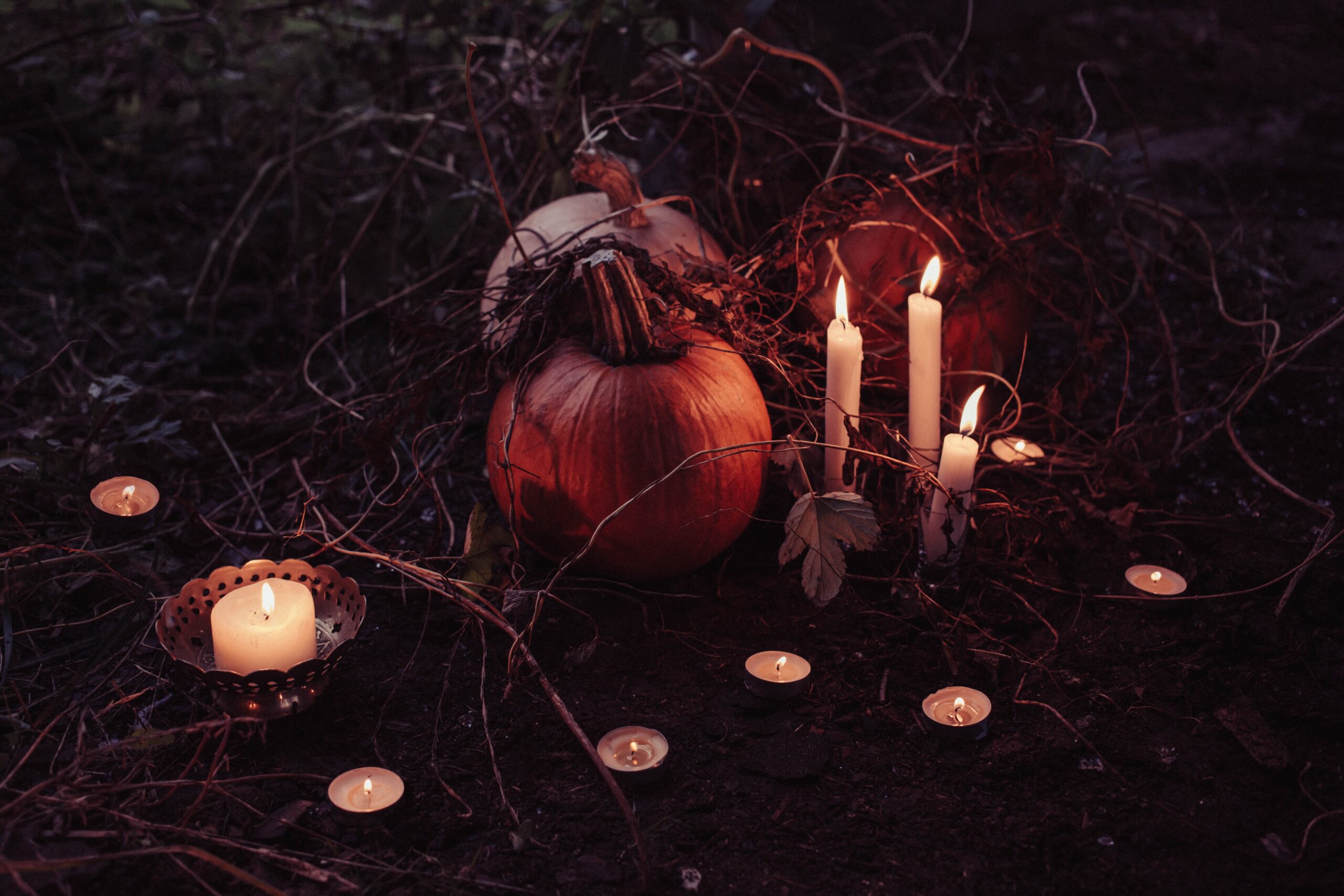 A spooky setting with two pumpkins outside and candles